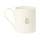 An off-white ceramic mug featuring a small, decorative speckled egg illustration on the front, set against a plain white background.