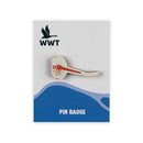 A small wooden pin badge shaped like a dragonfly with a red striped body and white wings, mounted on a branded display card.