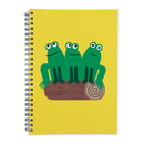 A spiral-bound notebook with a bright yellow cover featuring a cartoon illustration of three green frogs sitting on a brown log.