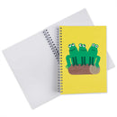 A spiral-bound notebook with a bright yellow cover featuring three green cartoon frogs sitting on a log, shown with the notebook blank cover open behind it on a white background.