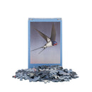A jigsaw puzzle box featuring a swallow in flight, with a pile of puzzle pieces in front on a white background.