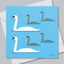 A square art print or card featuring a stylized illustration of four swans on a light blue background, with two white swans and two gray swans, placed over a white envelope on a gray surface.